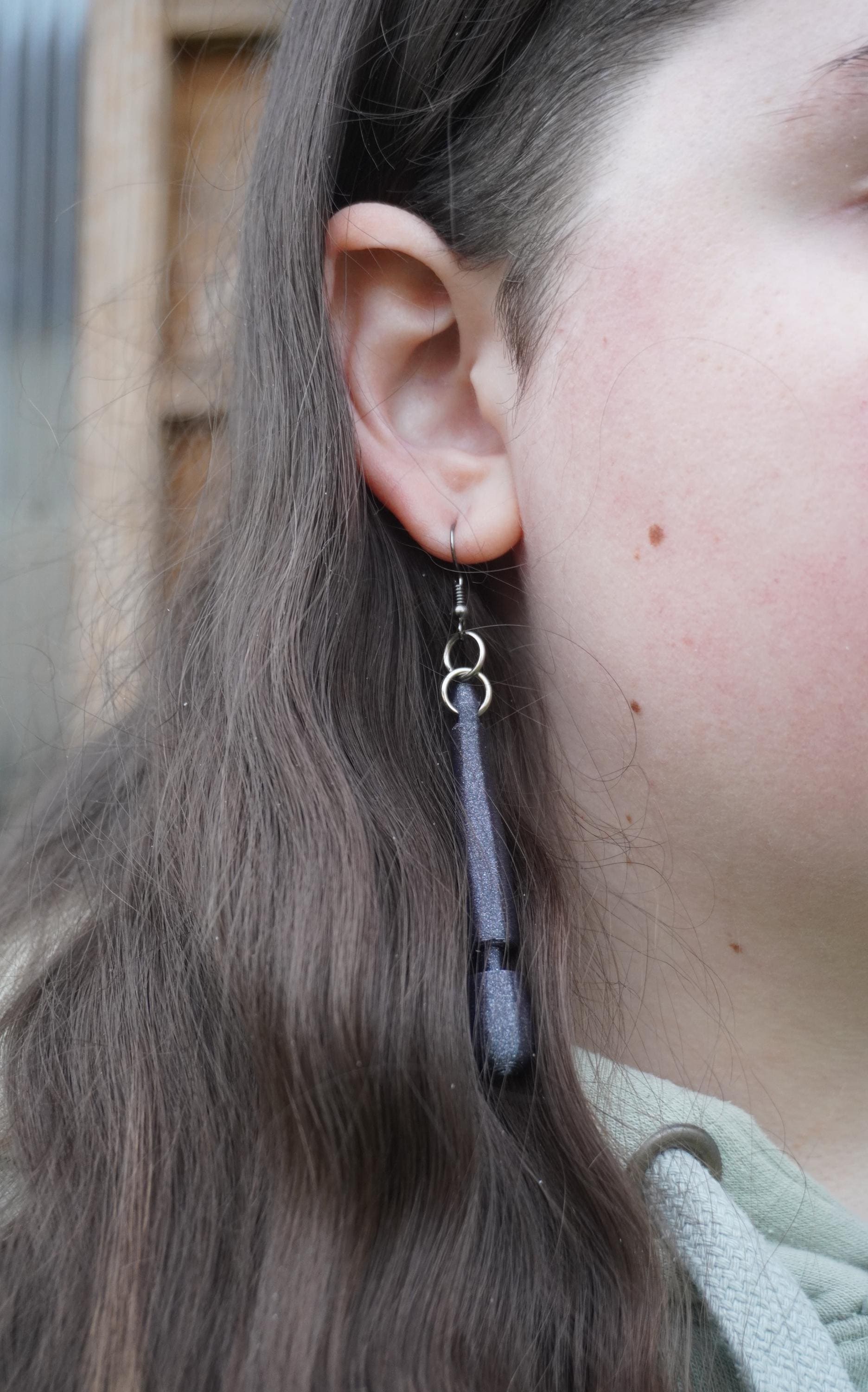 May include: A pair of dangle earrings with a dark grey, textured, elongated pendant. The earrings have a silver hook and two silver rings. (etsy image id: 8005283521)