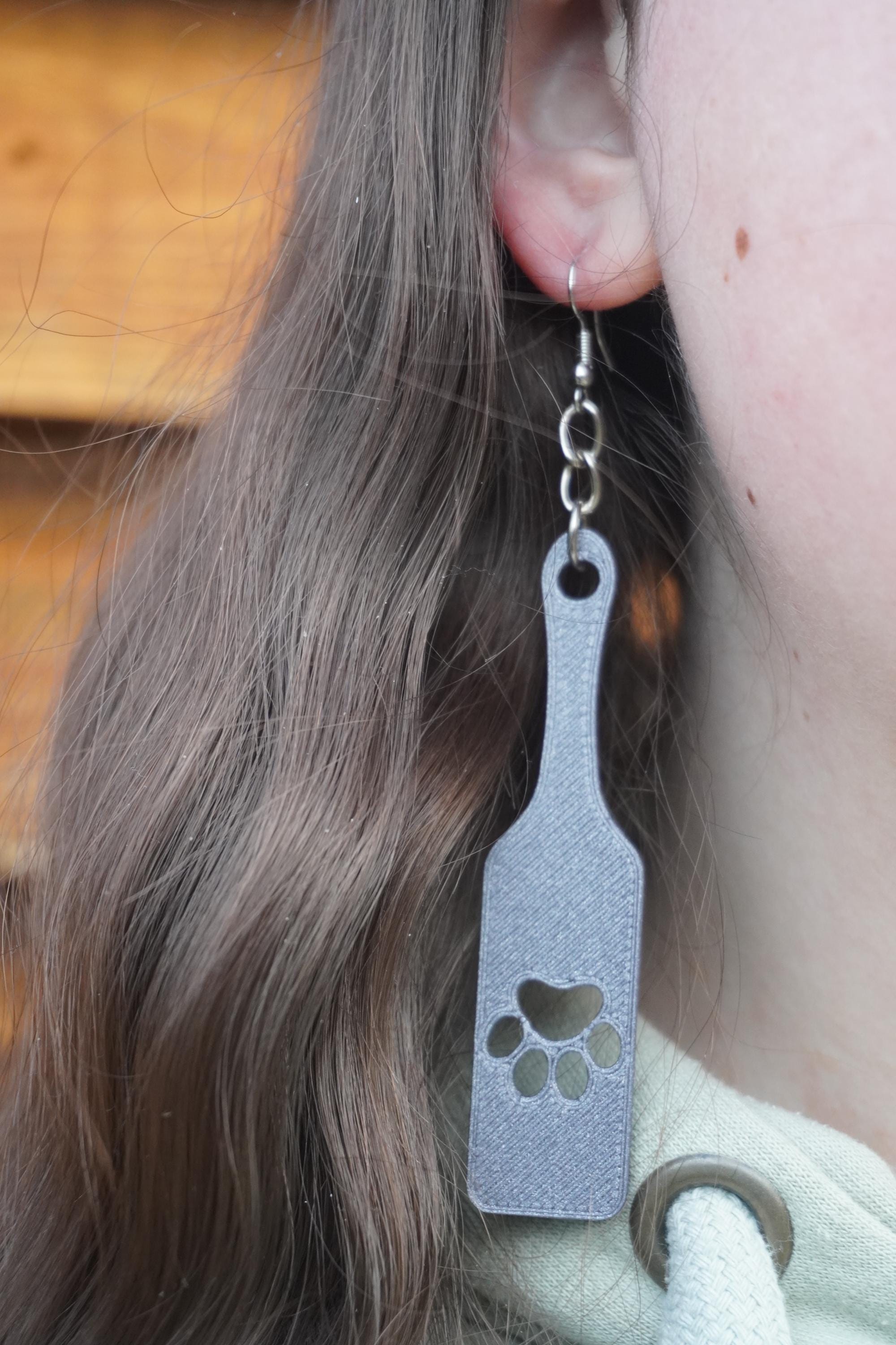 May include: Grey dangle earrings with a paw print design. The earrings are made of a textured material and have a silver hook. (etsy image id: 8005292459)